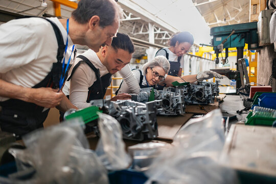 Workers inspecting metal equipment at industrial assembly line