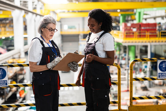 Factory workers discussing inspection checklist indoors
