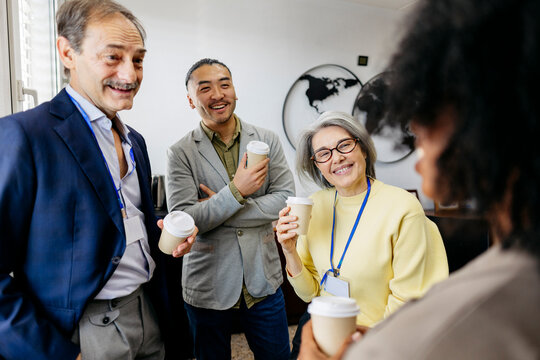 Smiling colleagues networking with coffee during a seminar break
