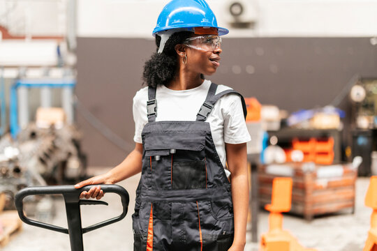 Industrial worker wearing safety gear operating a pallet jack