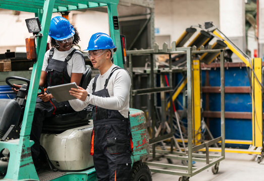 Factory workers using tablet near forklift during maintenance
