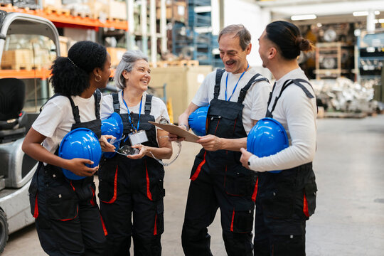 Happy warehouse workers discuss operations indoors