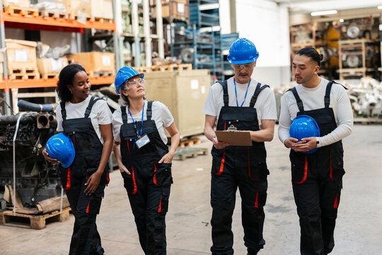 Team of factory workers walking and discussing in a warehouse