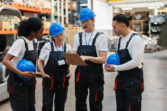 Workers discussing project on clipboard in warehouse