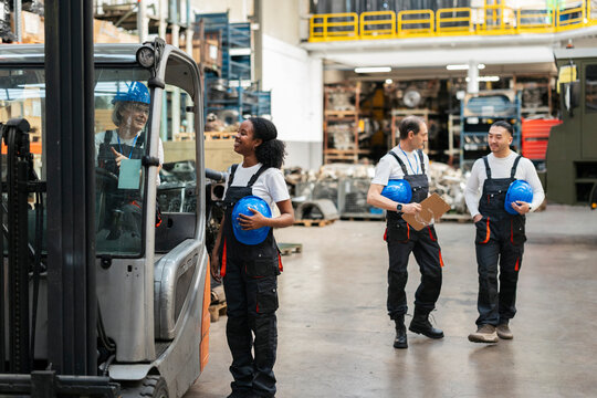 Warehouse workers talking by a forklift indoors