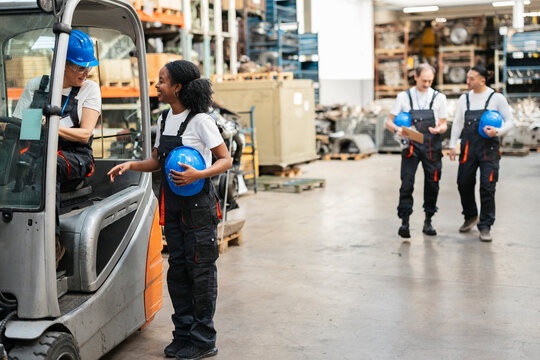 Colleague talking to forklift driver inside warehouse
