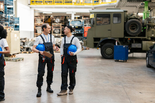 Staff discussing mechanical operation in a large warehouse