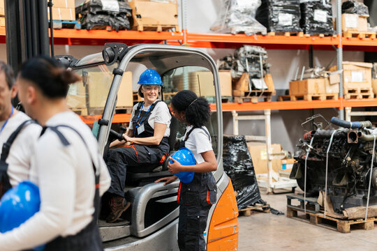 Workers discussing logistics by a forklift in a warehouse