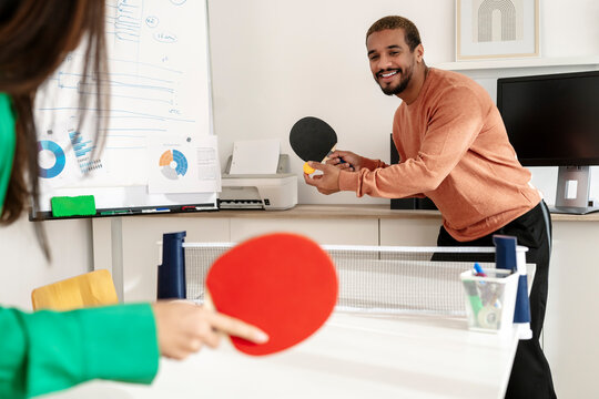 Smiling businessman playing table tennis with colleague in office