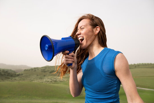 Activist in blue shirt shouting into a megaphone outdoors
