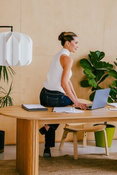 Businesswoman sitting on modern office desk working on laptop