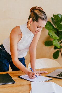 Business manager standing at desk and writing on clipboard