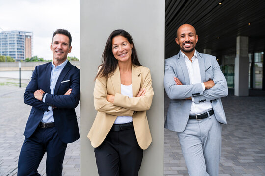 Confident real estate agents standing outdoors with crossed arms