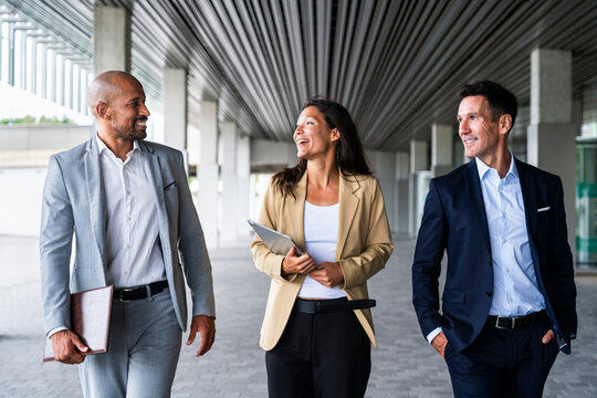 Smiling coworkers walking and talking in the financial district