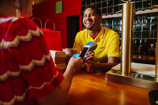 Customer making contactless payment to bartender at restaurant