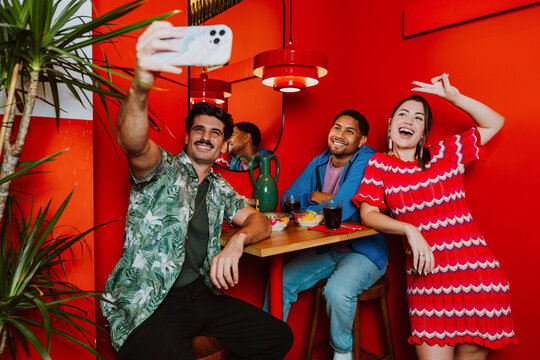 Friends taking a selfie while dining at a vibrant red restaurant