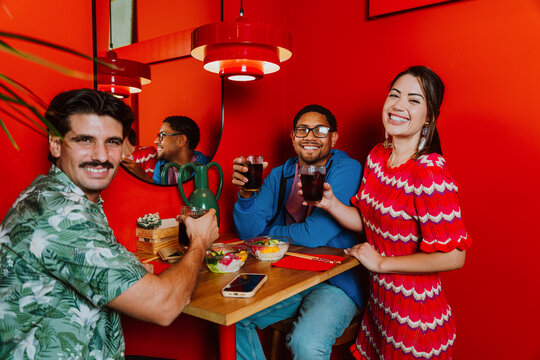 Friends smiling and eating poke at a red restaurant