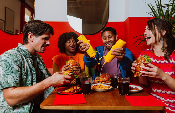 Friends joking with mustard while eating at a restaurant