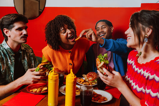 Diverse friends eating burgers and laughing in a restaurant