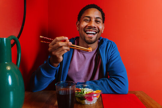 Happy diner eating a healthy poke bowl indoors