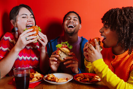 Friends eating burgers and laughing together at a restaurant