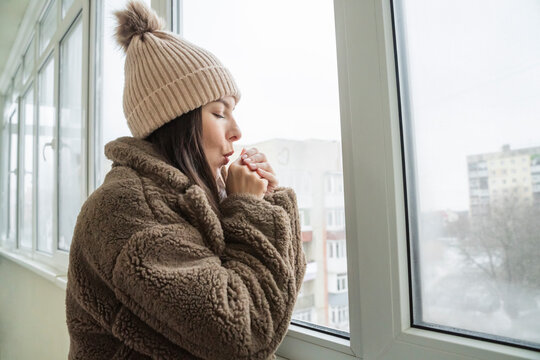 Woman blowing on hand to warm up in cold house