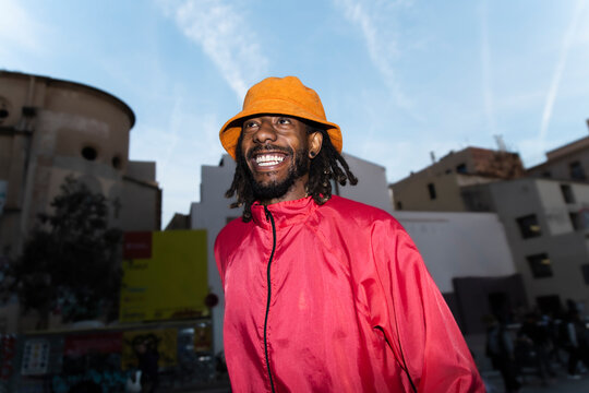 Smiling tourist in streetwear looking at camera at night in Barcelona