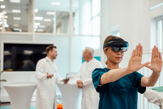 Doctor using virtual reality in a medical office with colleagues discussing in the background