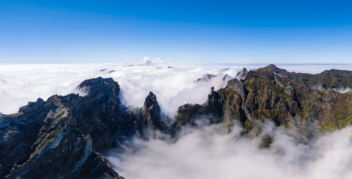 Aerial view of volcanic peak above clouds at Pico do Arieiro