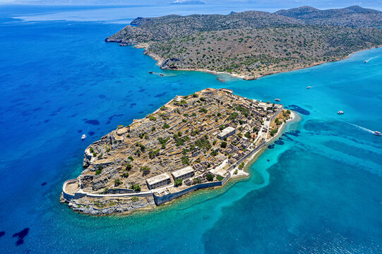 Aerial view of Spinalonga island in Crete, Greece, Europe, showing historic ruins, stone walls, and turquoise waters of the Aegean Sea.