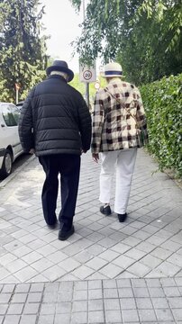 Se&ntilde;ores mayores elegantes y arreglados caminando matrimonio anciano de paseo sombrero viejos andando senior age en pareja walking old couple elderly 