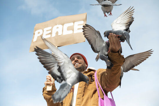 Activist holding peace sign with flying pigeons outdoors in Barcelona