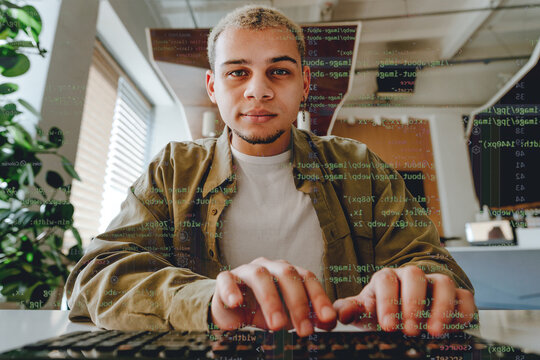 Programmer typing on keyboard with code overlay in the office