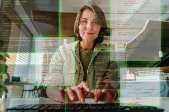 Businesswoman coding on laptop in office with digital interface