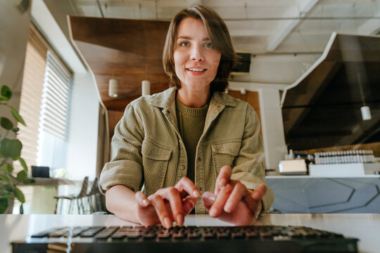 Businesswoman coding on laptop in modern office looking at camera