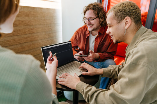 Smiling team of programmers coding on laptop in office