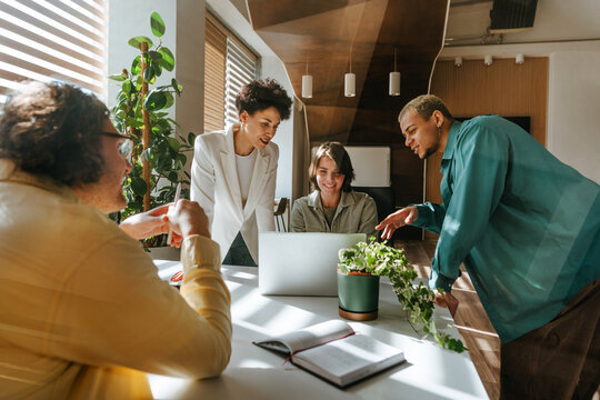 Colleagues discussing project around laptop in modern office