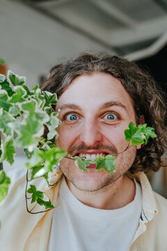Businessman playfully biting green plant in modern office