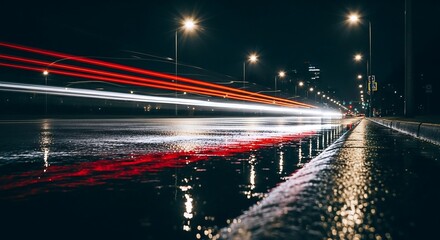 Fototapeta premium Abstract light trails illuminate a wet city street at night with reflections on the asphalt