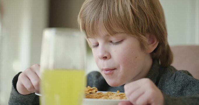 Kid Boy Eats Corn Flakes Meal in Kitchen. 4K 10-bit
