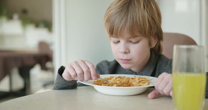 Kid Boy Eats Corn Flakes Meal in Kitchen. 4K 10-bit