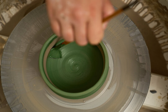 Handmade ceramics branding image showing green underglaze application on a wheel.