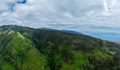 Naklejka premium Aerial drone view of the Madeira coastline with steep cliffs, Atlantic Ocean, and natural landscape. Calm travel scene with typical Portuguese island scenery.