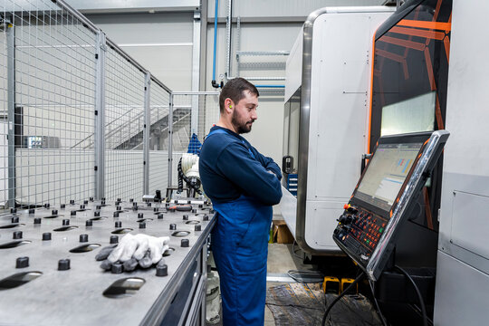 Young maintenance engineer standing by computer in modern factory