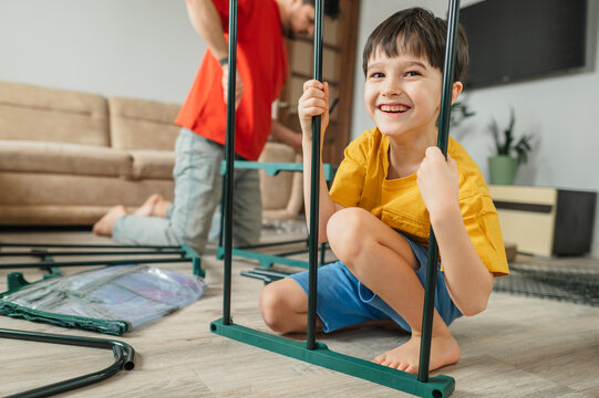 Smiling boy and father assembling furniture together in living room