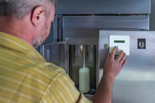 Man using milk vending machine on farm for fresh milk in countryside