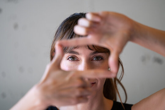 Photographer making finger frame gesture looking at camera
