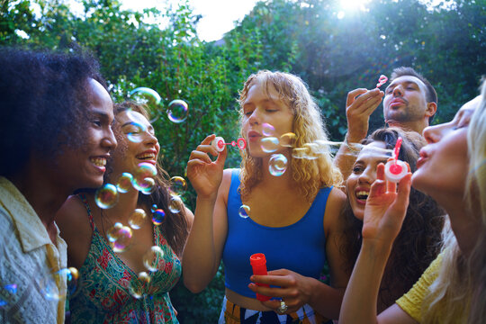 Friends blowing bubbles outdoors at a carefree summer party