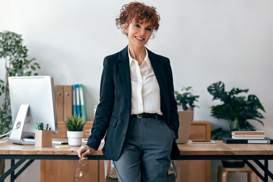 Smiling entrepreneur leaning on office desk