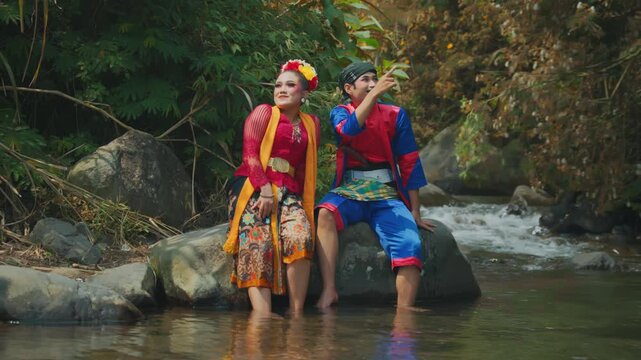 Javanese Dance Couple Sitting on Rock Pointing at Scenery